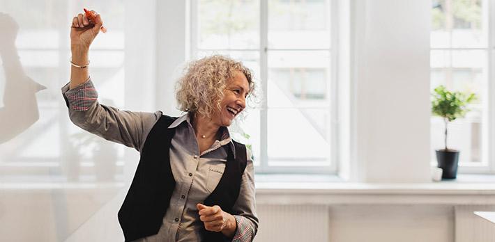 A mature student begins to write on a blank whiteboard.