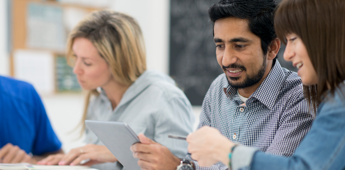 Adult learners using a tablet.