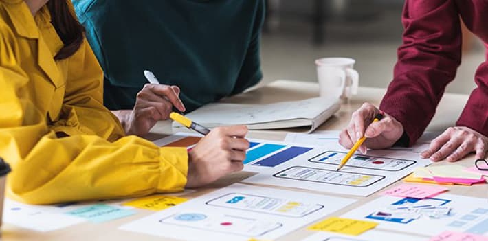 People collaborating on prototype ideas using paper and pencils.