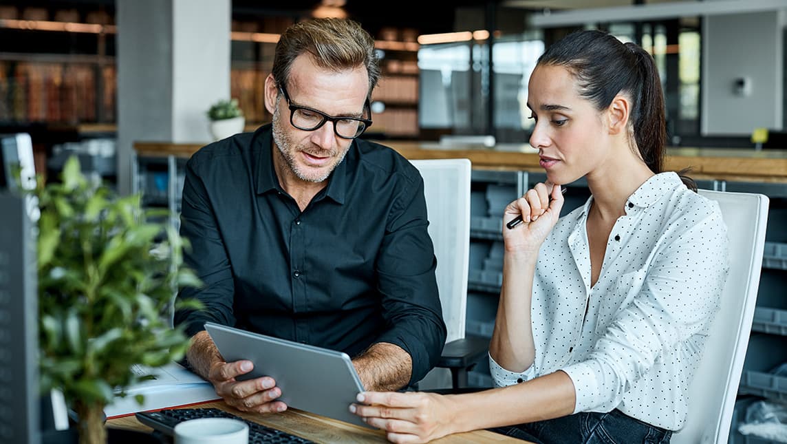Colleagues looks at a tablet screen.