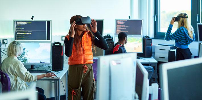 Students in a classroom environment working digitally with VR headsets.