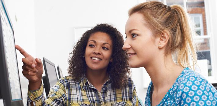 Female teacher working with a student at a computer