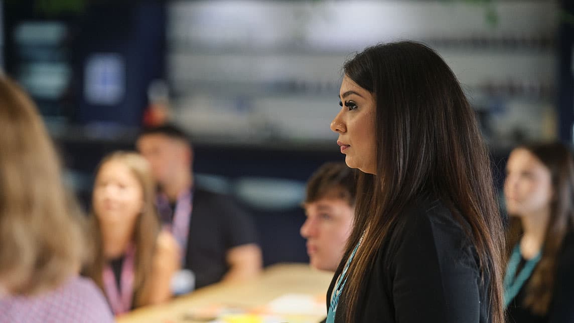 A female staff member standing in a meeting.