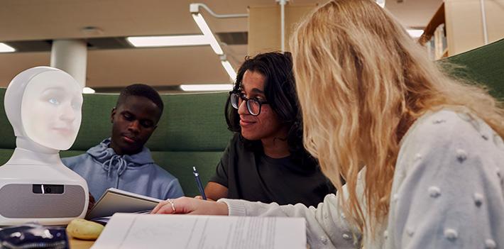 Robot with students in study setting.