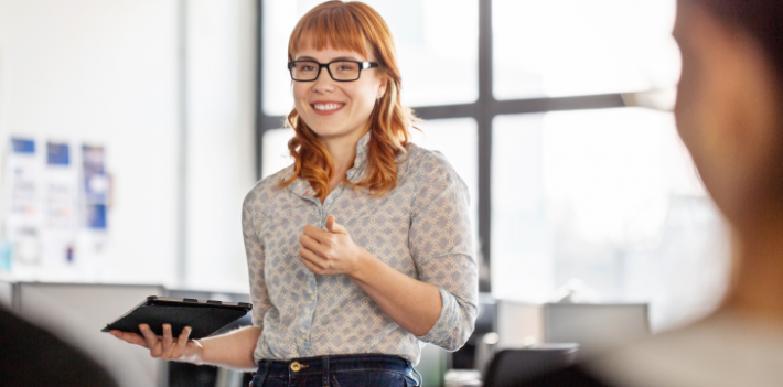 A woman smiling with a tablet in her hand.