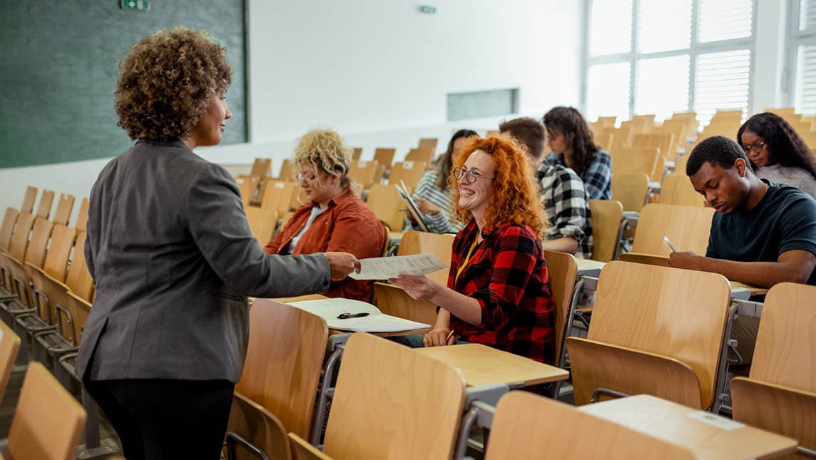 A female student handing her test paper to her tutor.