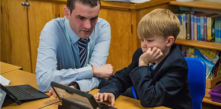School teacher and boy looking at a laptop.
