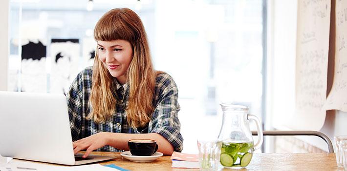 Woman working at a laptop in front of a bright window.